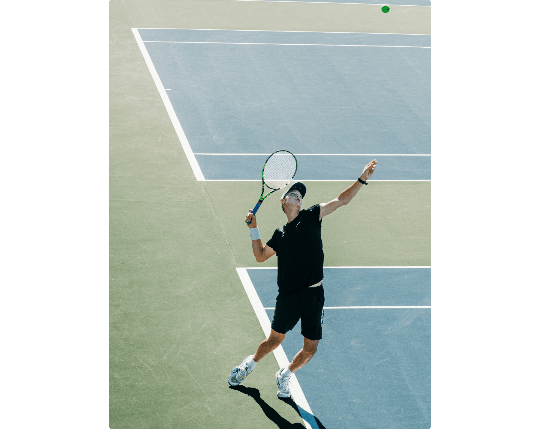 A tennis player on hardcourt is about to hit a serve.