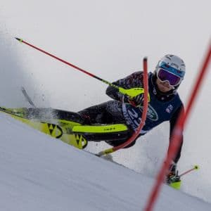 A college skier doing a left turn on a slalom course.