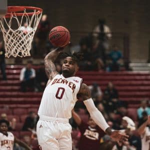 A basketball student-athlete from the University of Denver dunking a basketball.