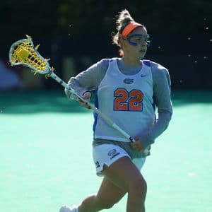 A college lacrosse player from the University of Florida carrying the ball in her stick.