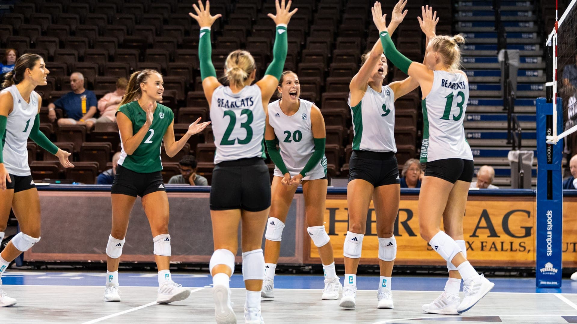 College-Volleyballteam (Bearcats) feiert zusammen auf dem Spielfeld in der Sporthalle während eines Spiels.