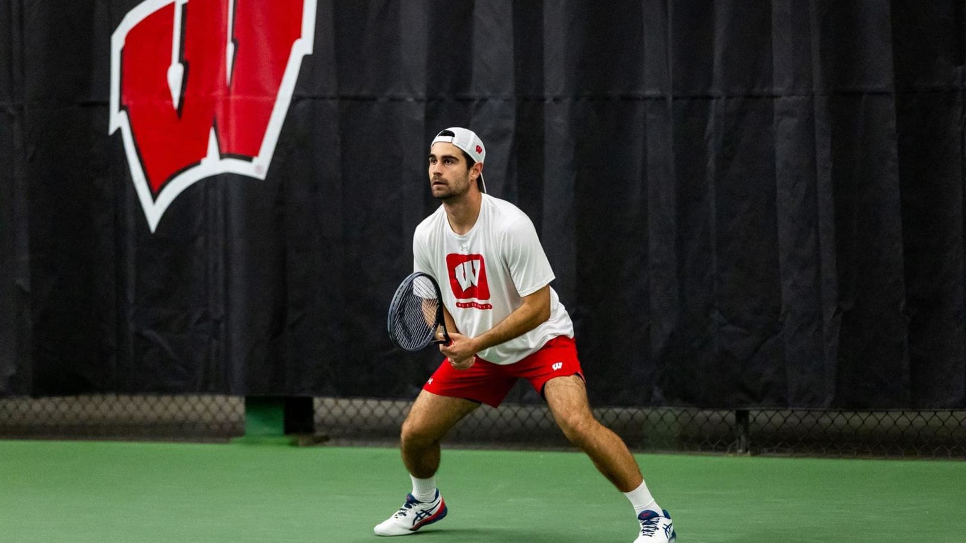 Gabriel Huber beim College-Tennis an der University of Wisconsin - Madison College-Tennisspieler Gabriel Huber von der University of Wisconsin - Madison konzentriert beim Warten auf den Ball auf seiner Seite des Platzes.