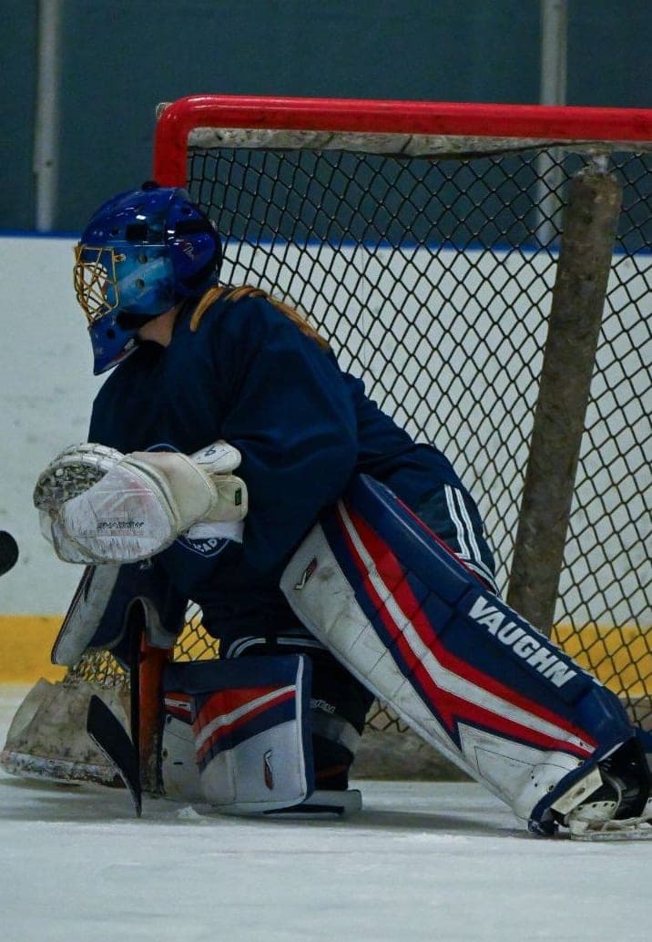 College Ice Hockey Goalkeeper Guarding the Goal | Smarthlete An ice hockey goalkeeper in blue and red guarding the goal.