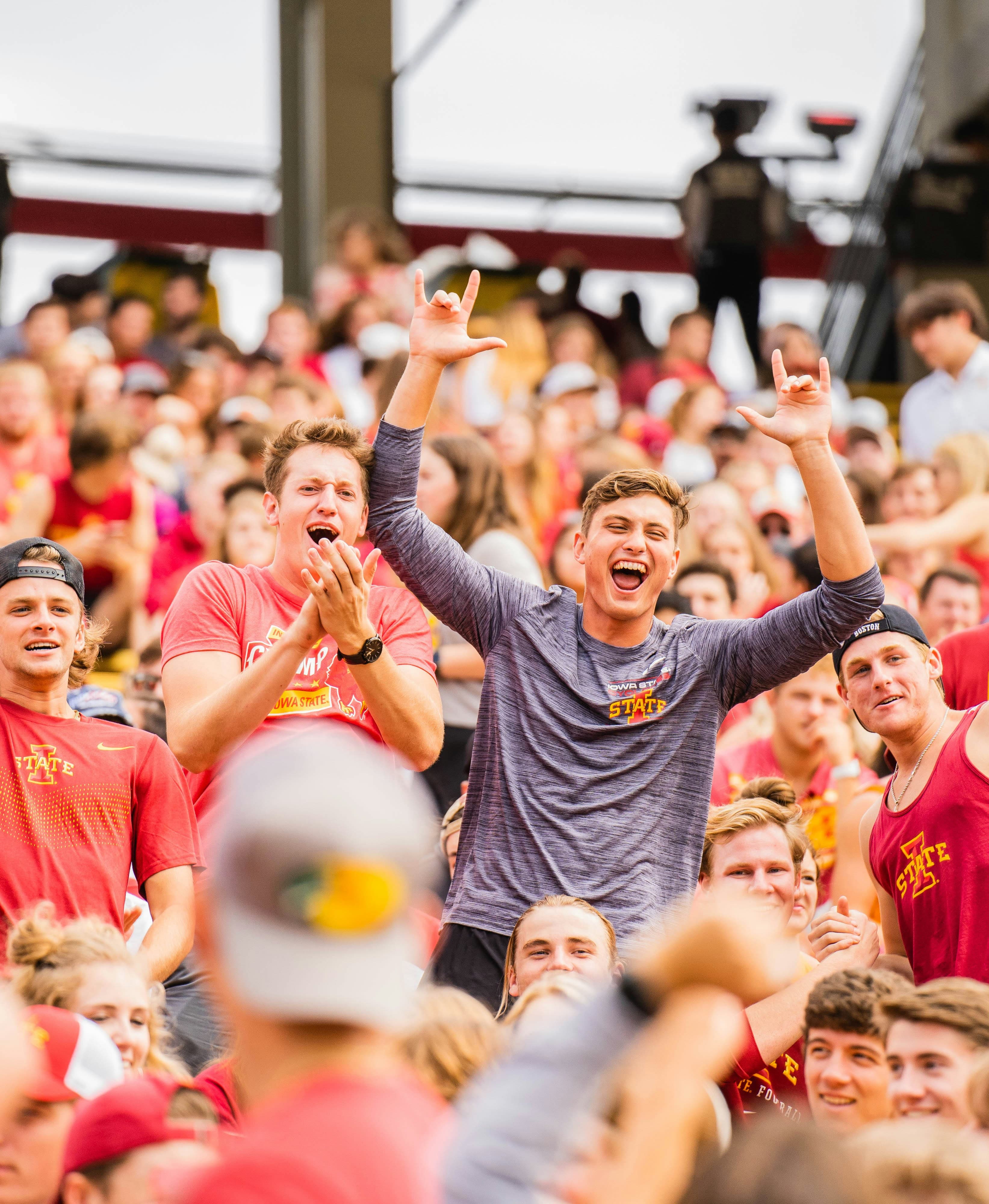 Discover College Sports Scholarships A large crowd of enthusiastic collegiate fans in red and gray gear cheering in a stadium during a game.