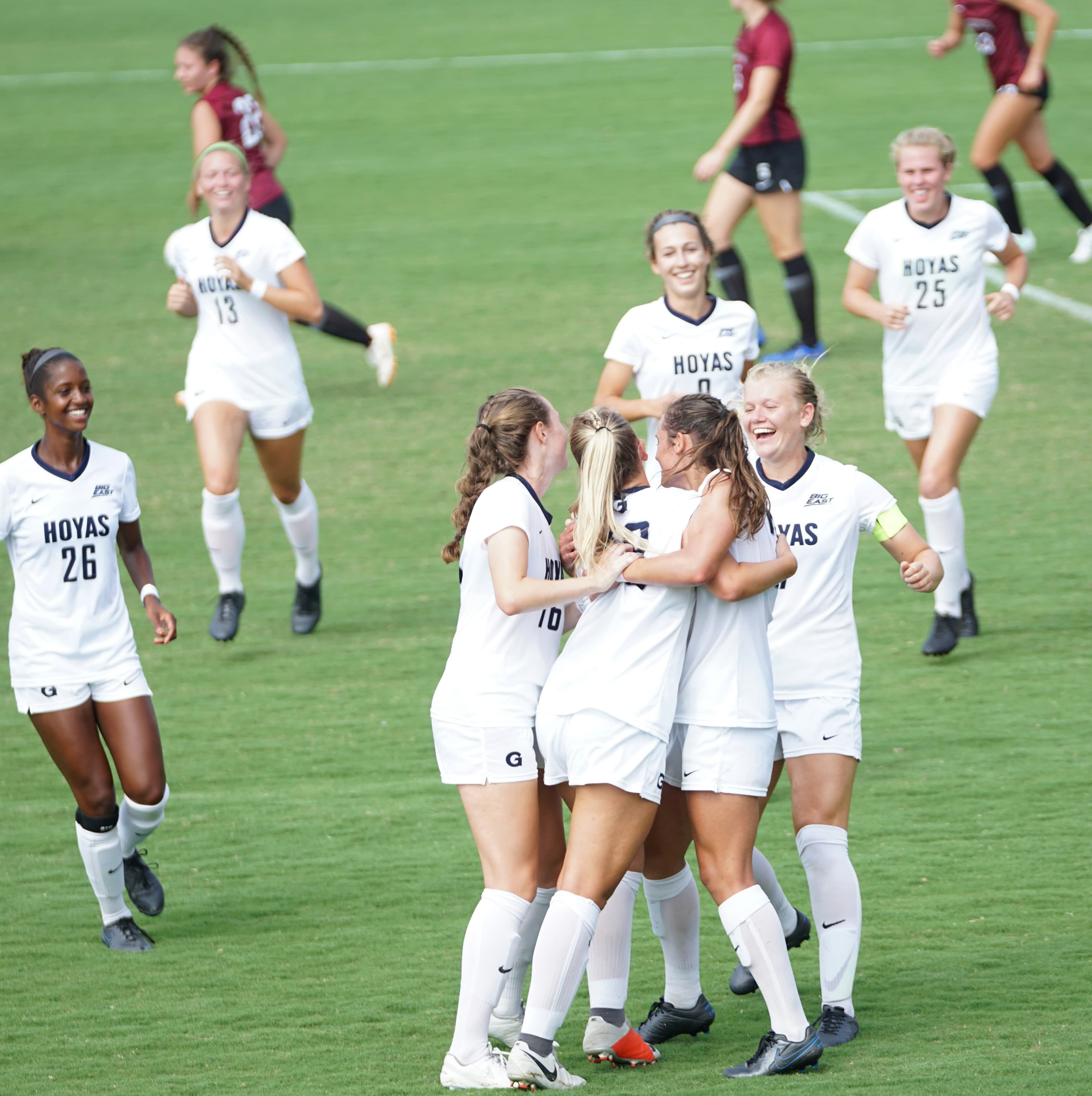 College Soccer Players Celebrating Together | Smarthlete Female college soccer players hugging and celebrating together on a soccer field.