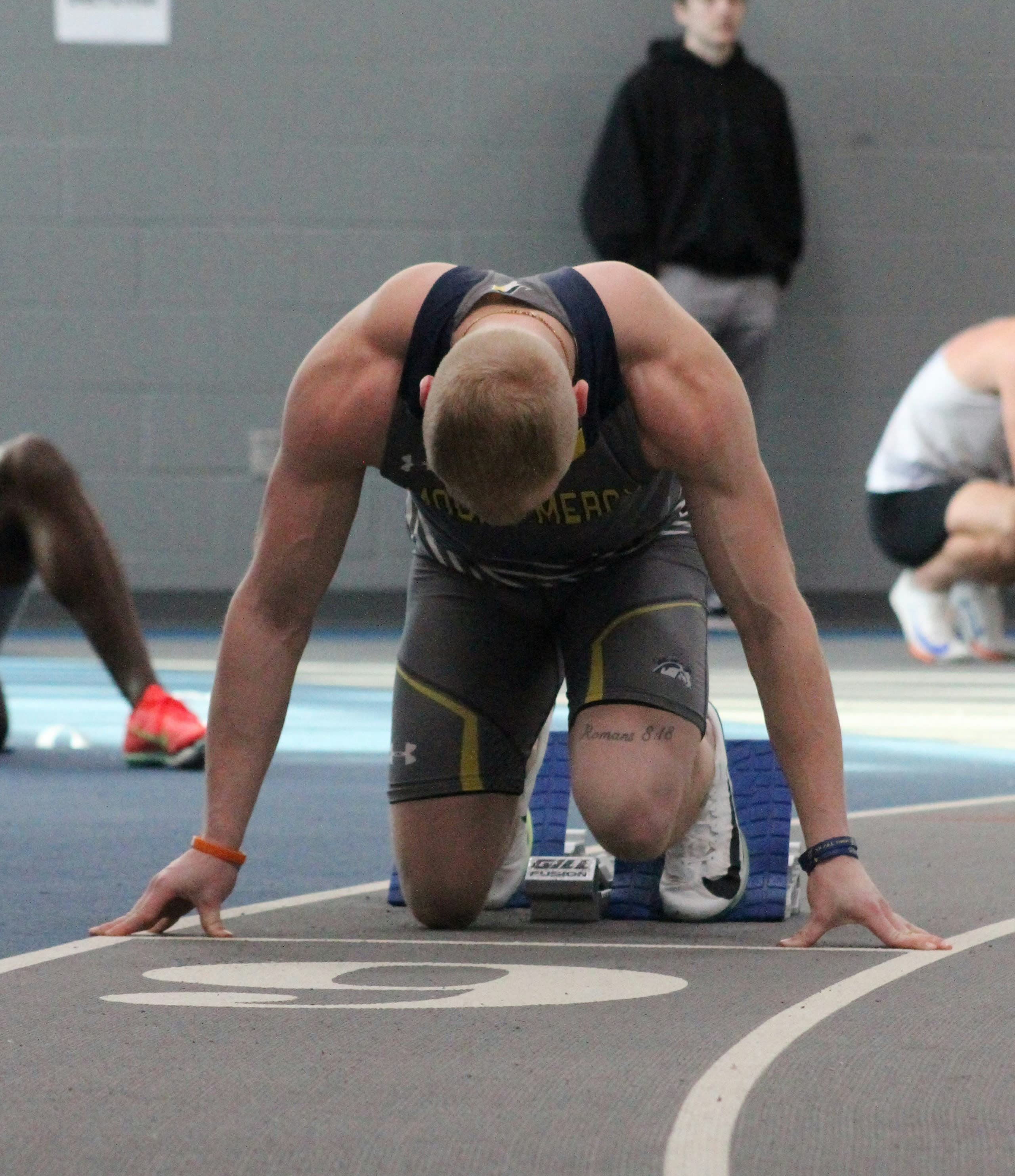 Male College Track & Field Athlete at Sprint Race Start | Smarthlete Male collegiate athlete at the start of a sprinting race.