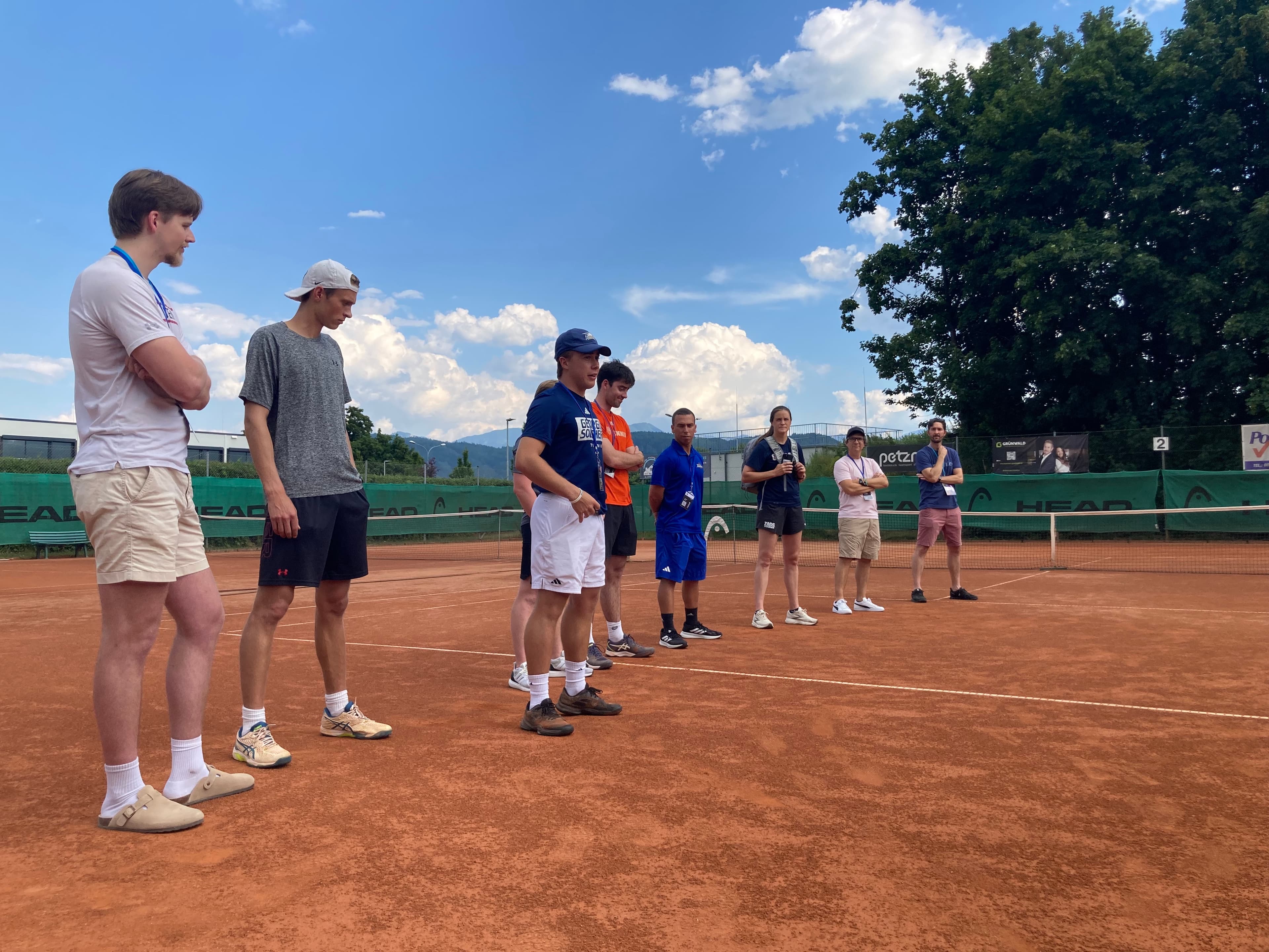 College Tennis Coaches and Recruiting Experts at the Smarthlete Showcase A group of college tennis coaches and college recruiting experts standing on a clay court.